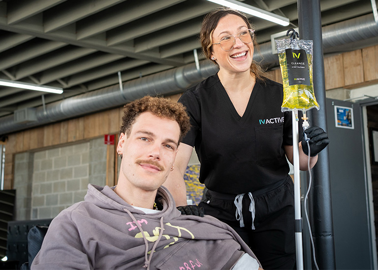 IV ACTIVE nurse holding a Cleanse IV drip bag beside a seated client