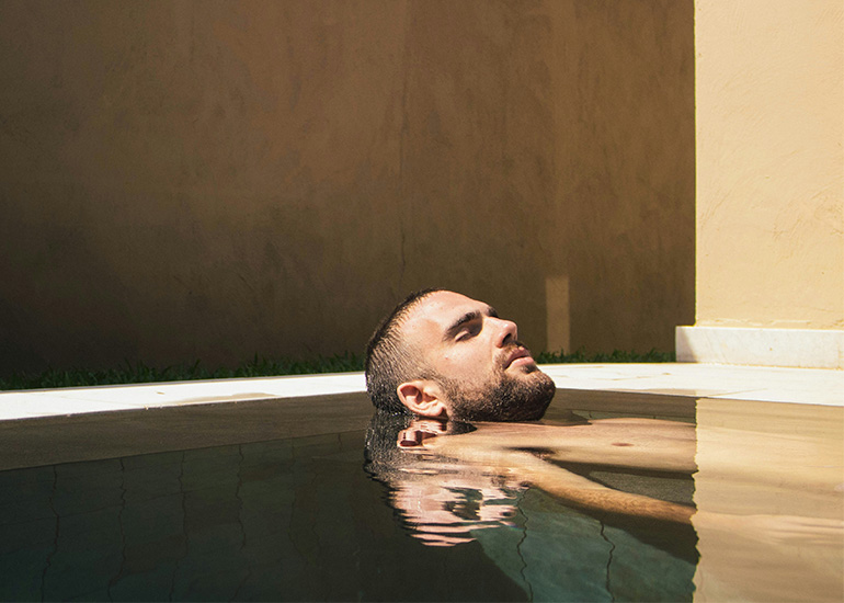 Man relaxing in a pool as part of a wellness routine